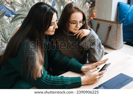 Gen Z influence on the development and popularity of short-form video content on social media platforms. Two girlfriend in cozy sweaters share a moment over smartphone and record video