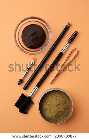 Flat lay composition with eyebrow henna and professional tools on orange background