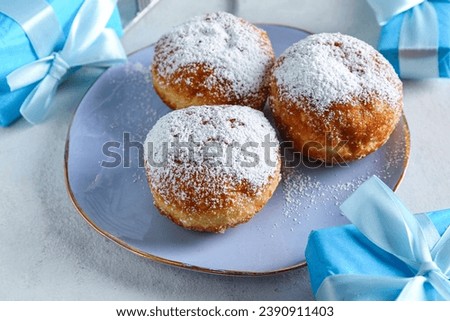 Plate with tasty donuts and gifts for Hanukkah celebration on light table, closeup