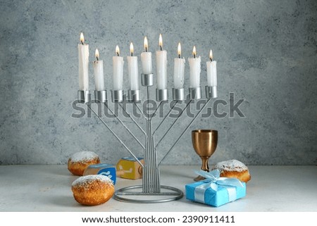 Menorah, donuts, cup and gift for Hanukkah celebration on grunge background