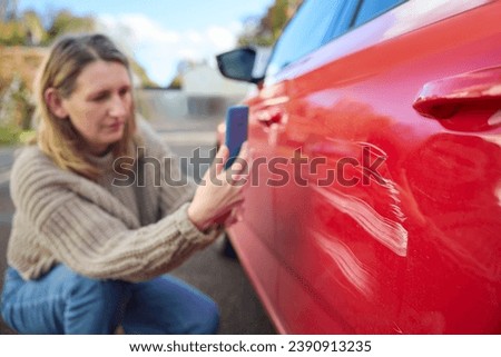 Mature Female Driver Taking Photo Of Damage To Car After Accident  On Mobile Phone