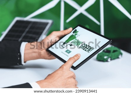 Businessman working in office developing plan or project on eco-friendly alternative energy with solar cell technology display on tablet screen for greener environment as apart of CSR effort. Gyre