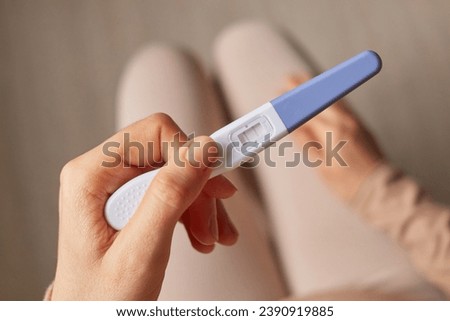Childbearing maternity. Unrecognizable woman hand holding pregnancy test with two stripes positive result future mother waiting for childbirth. Royalty-Free Stock Photo #2390919885