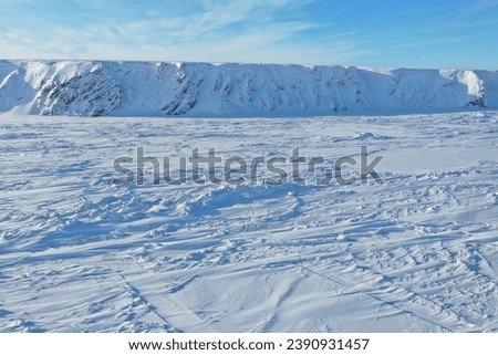 Landscape with snow covered mountains. Top view of an ice field and a wall of snow and ice. Aerial view of a snowy valley and an ice wall on the horizon.