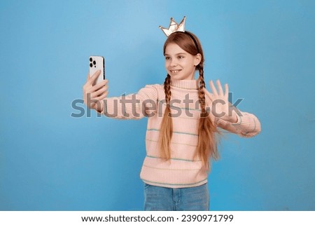 Little girl with crown have video call with her phone and waving hand.