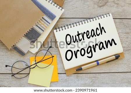 OUTREACH PROGRAM text on a notepad with a clip. glasses on stickers Royalty-Free Stock Photo #2390971961