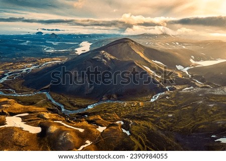 Dramatic aerial view of Sunset shines over volcanic mountain with river  flowing in Icelandic Highlands during summer at Iceland