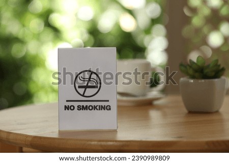 No Smoking sign on wooden table against blurred background