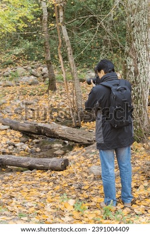 Rear view of adult man taking pictures of autumn landscape. Rascafria, Spain