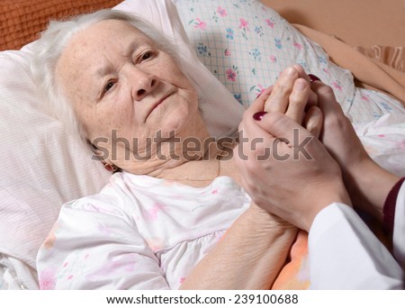 Young doctor holds the old woman's hand