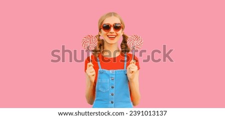 Summer portrait of happy smiling girl with colorful lollipop wearing red heart shaped sunglasses with cool girly hairstyle on pink background