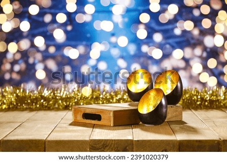 Black and gold christmas candles on wooden big table and free space for your decoration. Wooden vintage pedestal and blurred landscape of mountains. Winter snow and frost decoration. Mockup background
