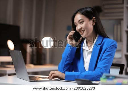 Businesswoman working overtime in the home office is using mobile phone to send messages and chat with colleagues, and analyzing monthly work schedule. Royalty-Free Stock Photo #2391025293