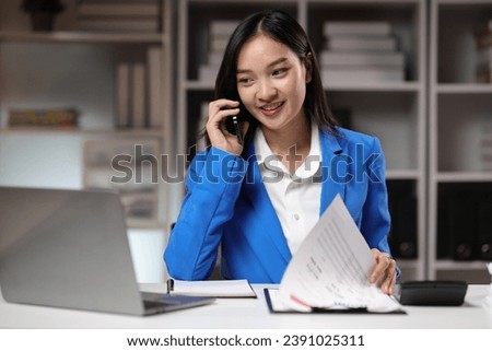 Businesswoman working overtime in the home office is using mobile phone to send messages and chat with colleagues, and analyzing monthly work schedule. Royalty-Free Stock Photo #2391025311