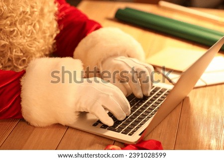 Santa Claus using laptop at table