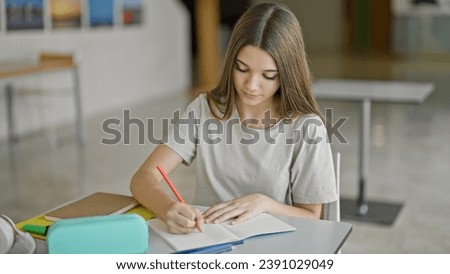 Young beautiful girl student writing on notebook thinking at library