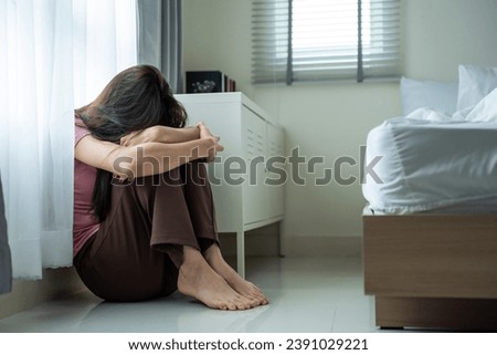 Asian young upset depressed woman sitting alone in living room at home. Attractive unhappy female feeling very sad, lonely and frustrated with life problem think of money debt, budget loss, bankruptcy Royalty-Free Stock Photo #2391029221