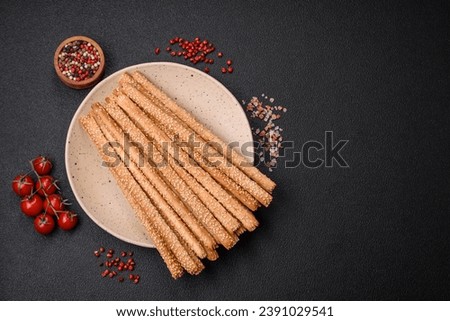 Delicious fresh grissini sticks with salt and sesame seeds on a dark concrete background Royalty-Free Stock Photo #2391029541