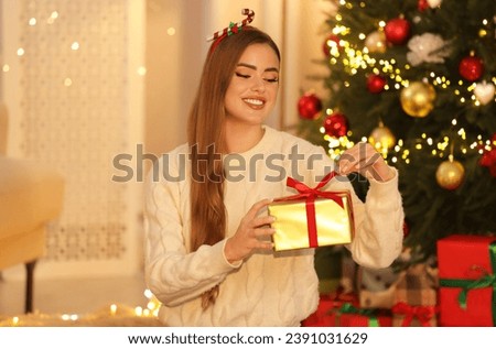 Beautiful young woman decorating Christmas gift at home