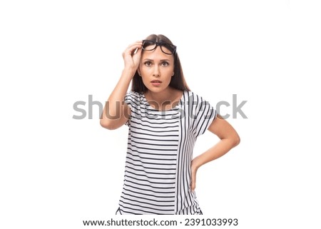 young european brunette woman in a striped sweater wears glasses for vision correction on a white background with copy space