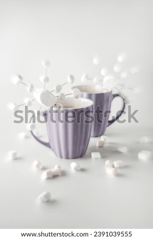 A purple mugs with hot coffee and marshmallows. Two cups with marshmallows in snowflake shapes.  Soft focus effect.