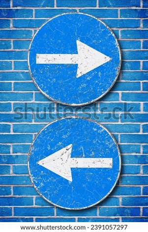 Old blue metallic arrow sign against an aged brick wall indicating to go left and right - concept image.