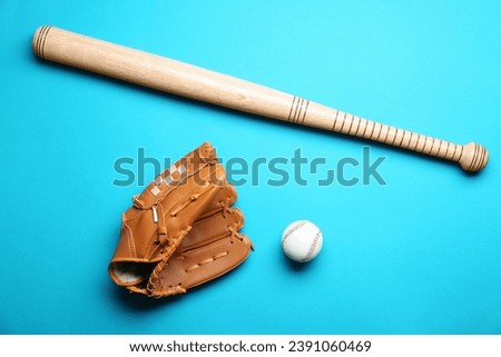 Baseball glove, bat and ball on light blue background, flat lay