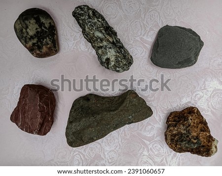 An artistic composition showcasing six distinct stones, each with unique shapes and colors, carefully arranged on a paper background, capturing the natural beauty of river stones.