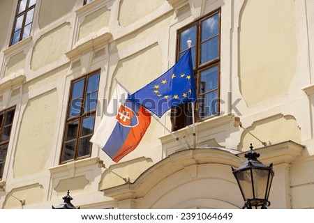 Slovakia flag and EU flag on the wall of a house. Flags in the facade of old building. Slovakia is a member of the European Union and the Eurozone.