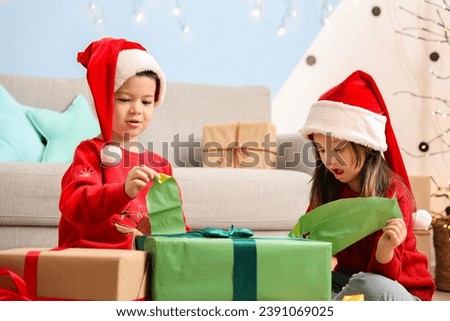 Adorable little children opening Christmas gift at home