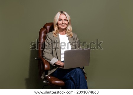 Photo of successful business specialist data analytic working on laptop sitting leather armchair isolated over khaki color background