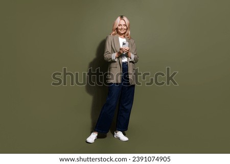 Full size photo of mature business lady jeans with jacket writing sms to employees announce 13 salary isolated on khaki color background