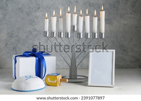 Menorah, blank picture frame, gift and Hanukkah symbols on grunge background