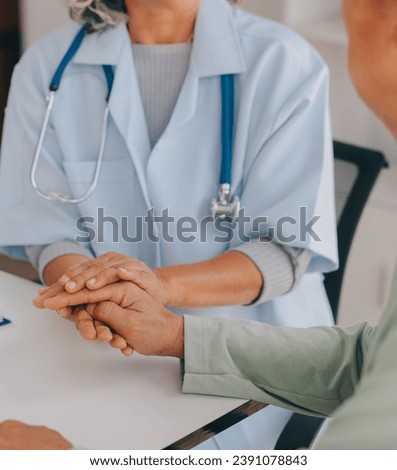 Doctor giving hope. Close up shot of young female physician leaning forward to smiling elderly lady patient holding her hand in palms. Woman caretaker in white coat supporting encouraging old person Royalty-Free Stock Photo #2391078843