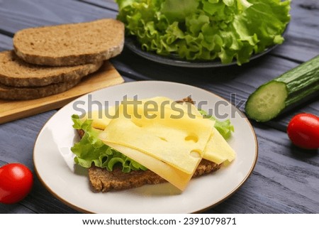 Tasty sandwich with cheese and lettuce in plate on grey wooden background, closeup Royalty-Free Stock Photo #2391079871