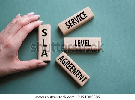 SLA - Service Level Agreement. Wooden blocks with word SLA. Businessman hand. Beautiful grey green background. Business and Service Level Agreement concept. Copy space.