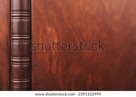 Family photo book with wooden cover. Opened Photo book on a green abstract blured background. Brown photo book. Wedding album with a hard cover. Services of a professional photographer and designer.