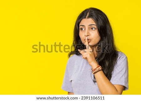 Shh be quiet please. Indian young woman presses index finger to lips makes silence gesture sign do not tells secret, stop talk gossip, confidential privacy. Arabian girl isolated on yellow background
