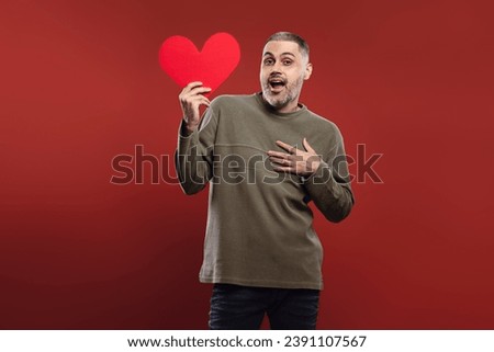 man holding a paper heart at face height