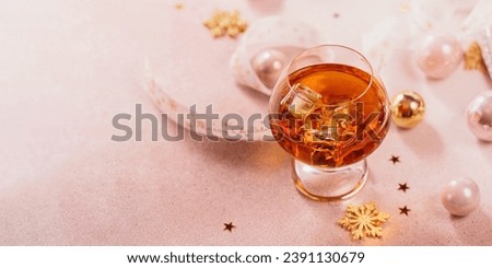Glass of whiskey or bourbon with festive Christmas decoration on light background. New Year, Christmas and winter holidays whiskey mood concept