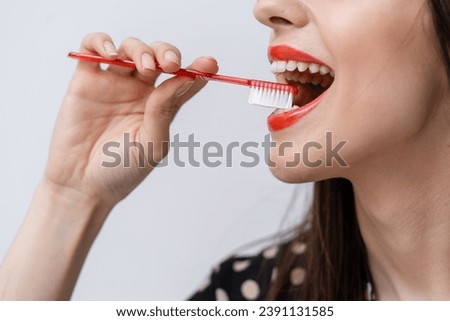 A woman brushing her teeth with a red toothbrush. A Woman Engaging in Oral Hygiene with a Vibrant Red Toothbrush Royalty-Free Stock Photo #2391131585
