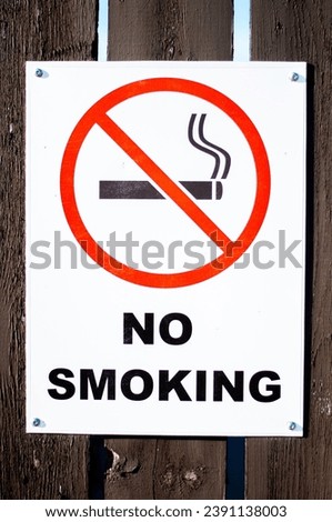 A vertical image of a no smoking sign posted up on a fence