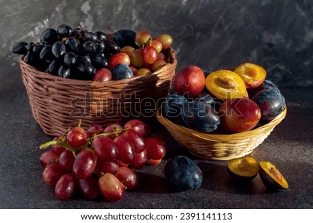 still life of grapes and plums in a basket