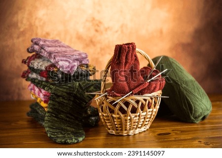 Colored yarn, knitting needles and other items for hand knitting on a dark wooden table.