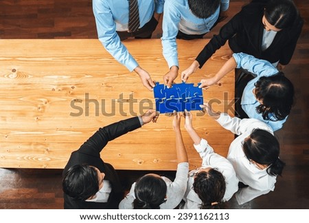 Multiethnic business people holding jigsaw pieces and merge them together as effective solution solving teamwork, shared vision and common goal combining diverse talent. Panorama top view. Meticulous Royalty-Free Stock Photo #2391162113