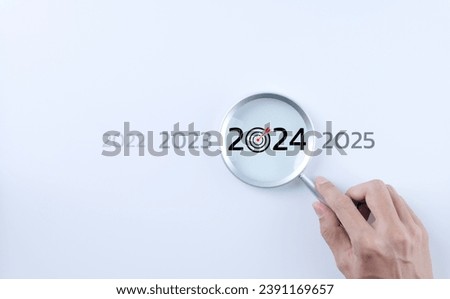 The 2024 new year business goals concept. A person holding a magnifying glass looking at the word year 2024 on white background. Business plan target strategy, Marketing trend 2024, Work focus,