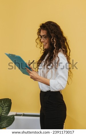 A businesswoman in a modern office analyzes reports, does paperwork, and contributes to company's growth. Positive and productive environment encourages teamwork and innovation.