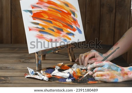 Female hands of the artist, with brushes and paints for drawing.