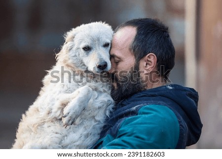 Lovely moment when mature man holding and hugging cute abandoned dog in shelter. Love, care and tenderness Royalty-Free Stock Photo #2391182603