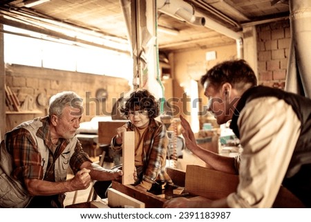 Young Boy Learns Woodworking Skills from His Elderly Grandfather and Father in a Workshop